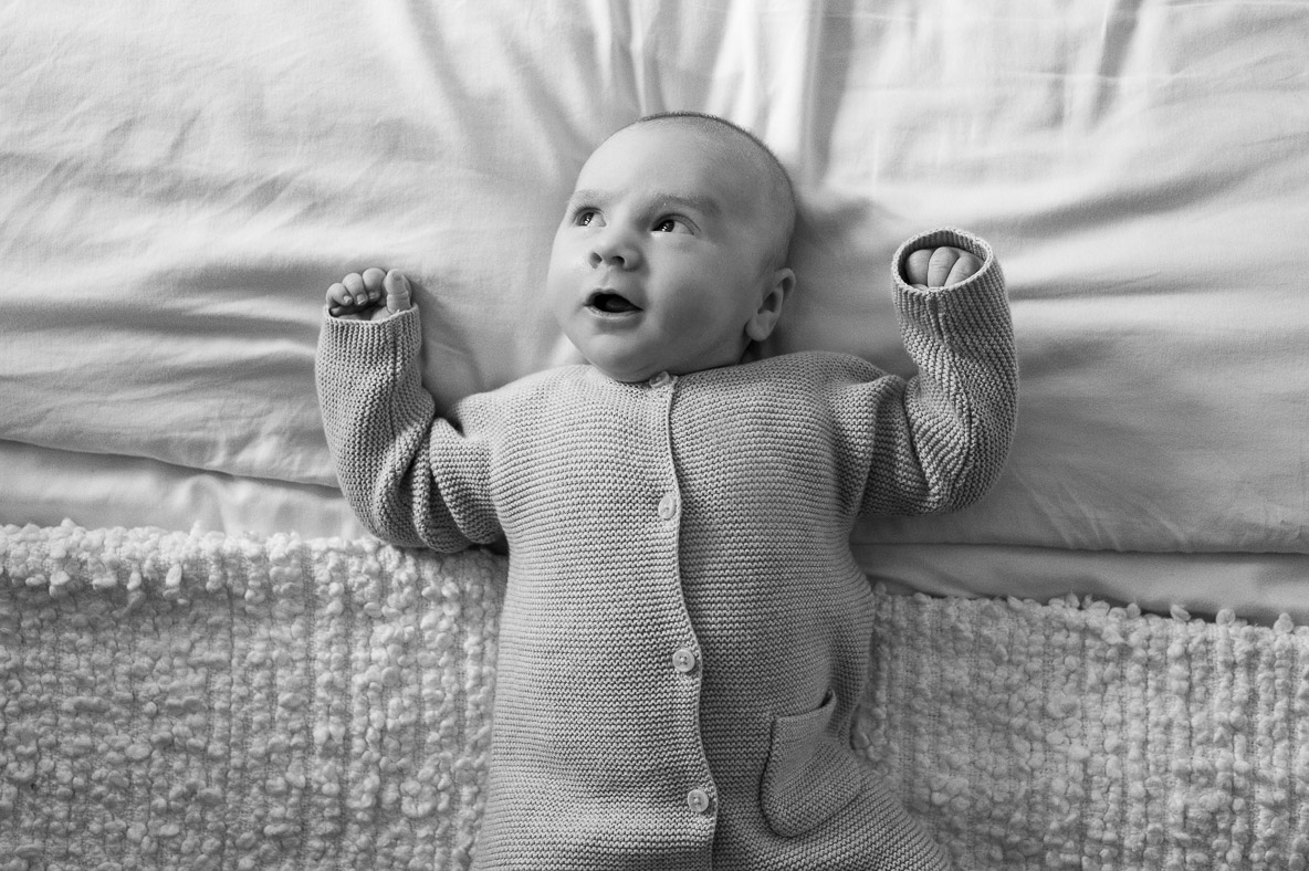 a 7 week old baby relaxes on the bed during a watford newborn photoshoot