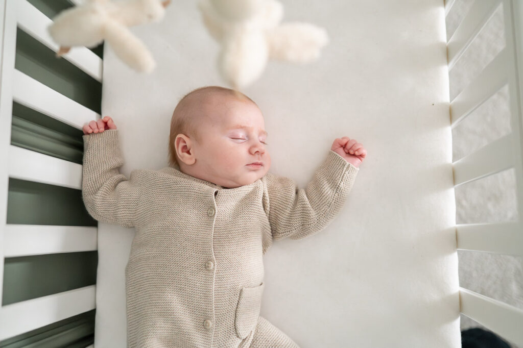 newborn sleeps soundly in his cot during an at home newborn photoshoot in Watford