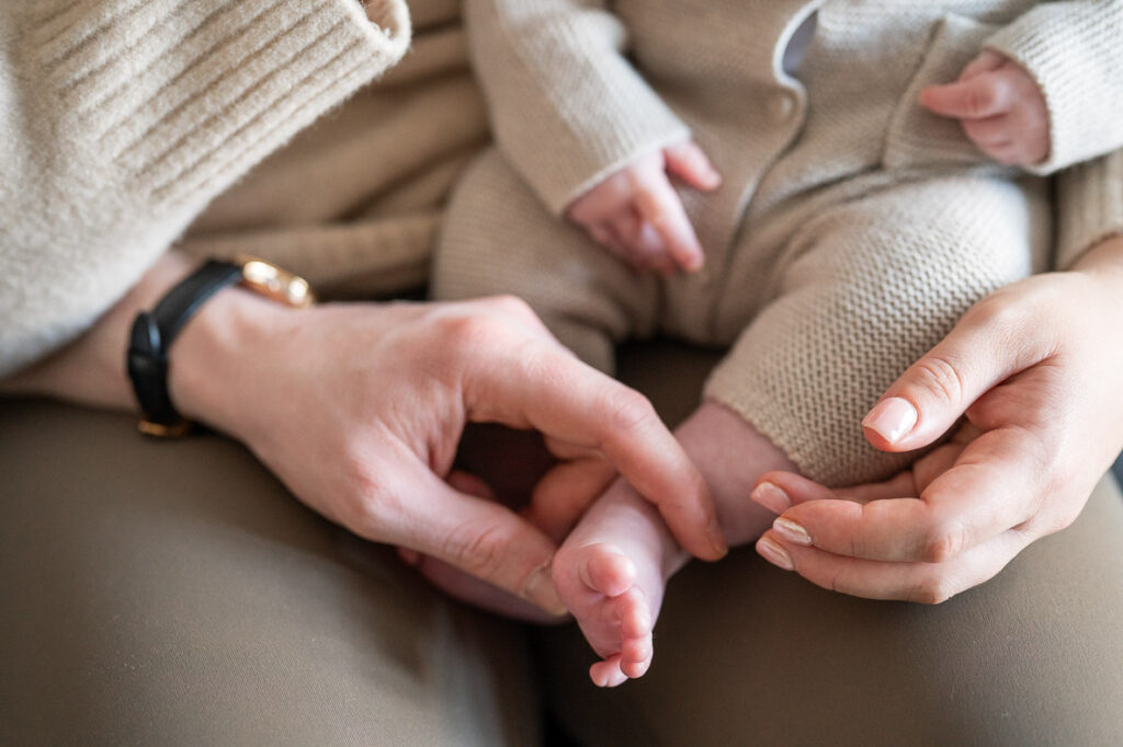 mum and dad caress a newborn baby's toes during a watford newborn photoshoot