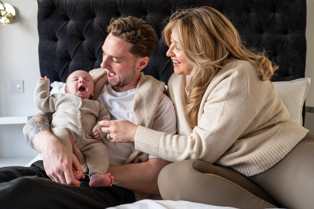 mum and dad cuddle their newborn whilst he has a cheeky yawn during a Watford newborn photoshoot