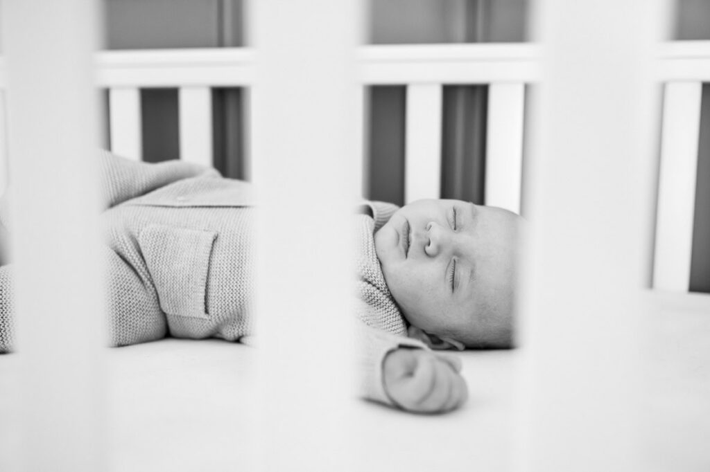 newborn sleeps soundly in his cot during a watford baby photoshoot