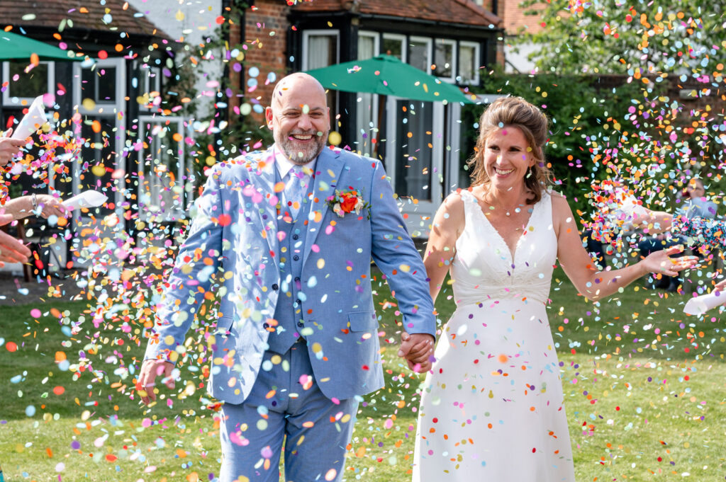 bride and groom under a colourful cloud of confetti old bull Hurley wedding photographer