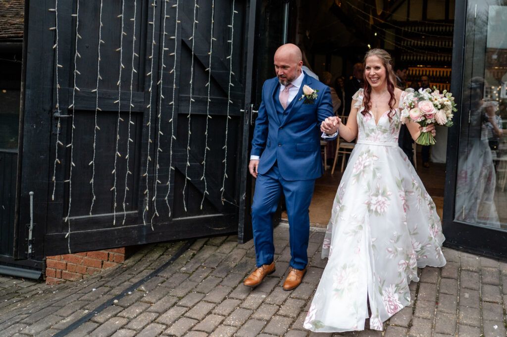 Kristin and Simon exiting the barn as newlyweds, smiling and joyful during their intimate Old Luxters Barn micro-wedding elopement.