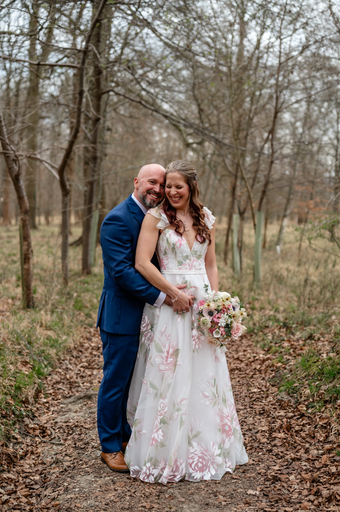Kristin and Simon strolling through the woods, chatting and laughing naturally during their Old Luxters Barn micro-wedding elopement.