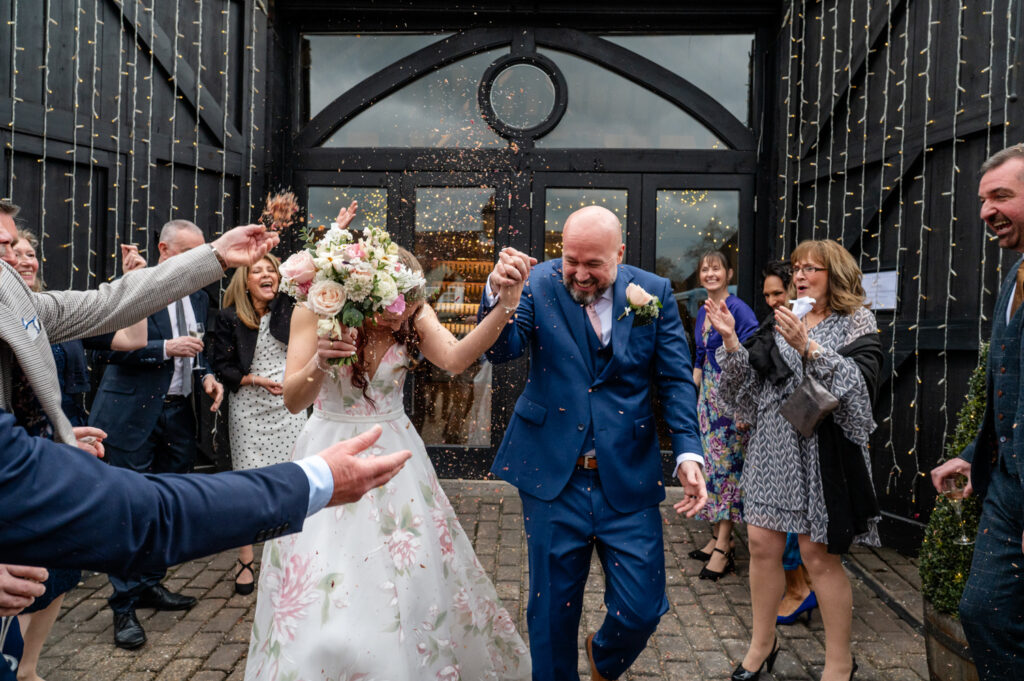 A fun and candid moment as confetti covers Kristin and Simon’s faces during their intimate micro-wedding elopement at Old Luxters Barn.