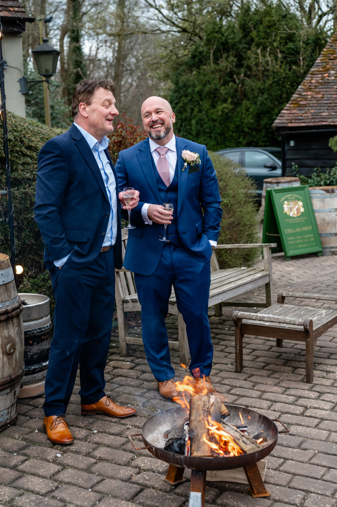 Evening courtyard vibes with friends and family enjoying fire pits and fairy lights at Kristin and Simon’s Old Luxters Barn micro-wedding elopement.