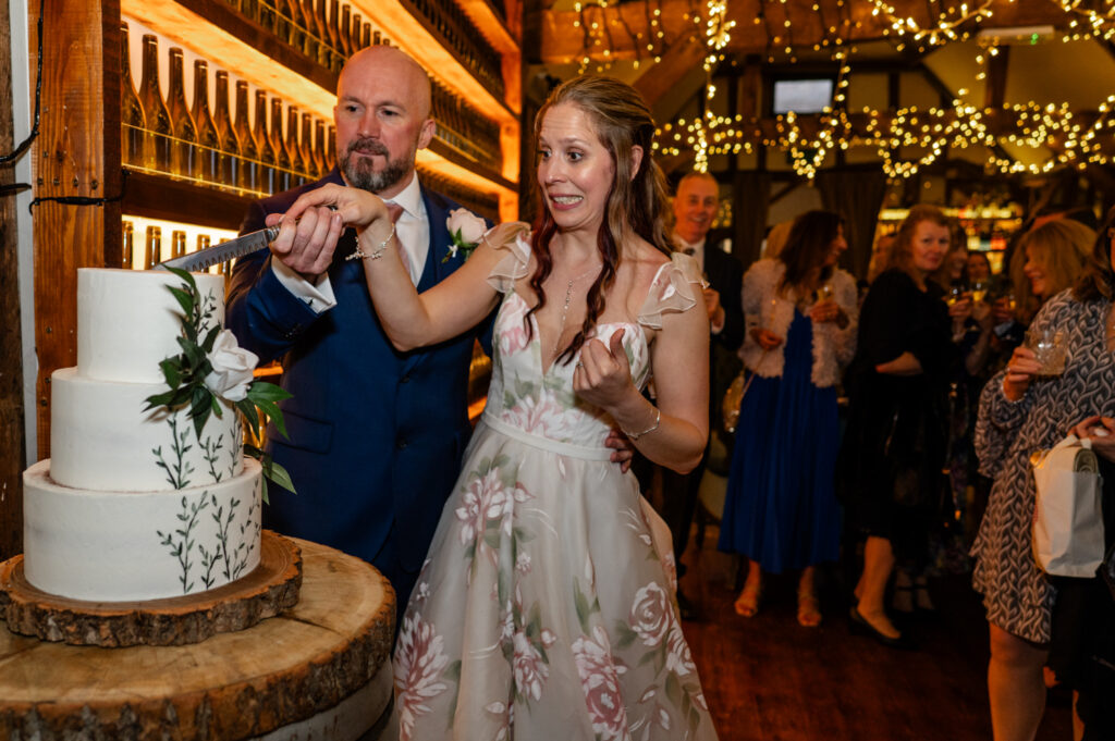 Kristin and Simon sharing a sweet, emotional moment together while cutting their cake at their intimate Old Luxters Barn micro-wedding elopement.