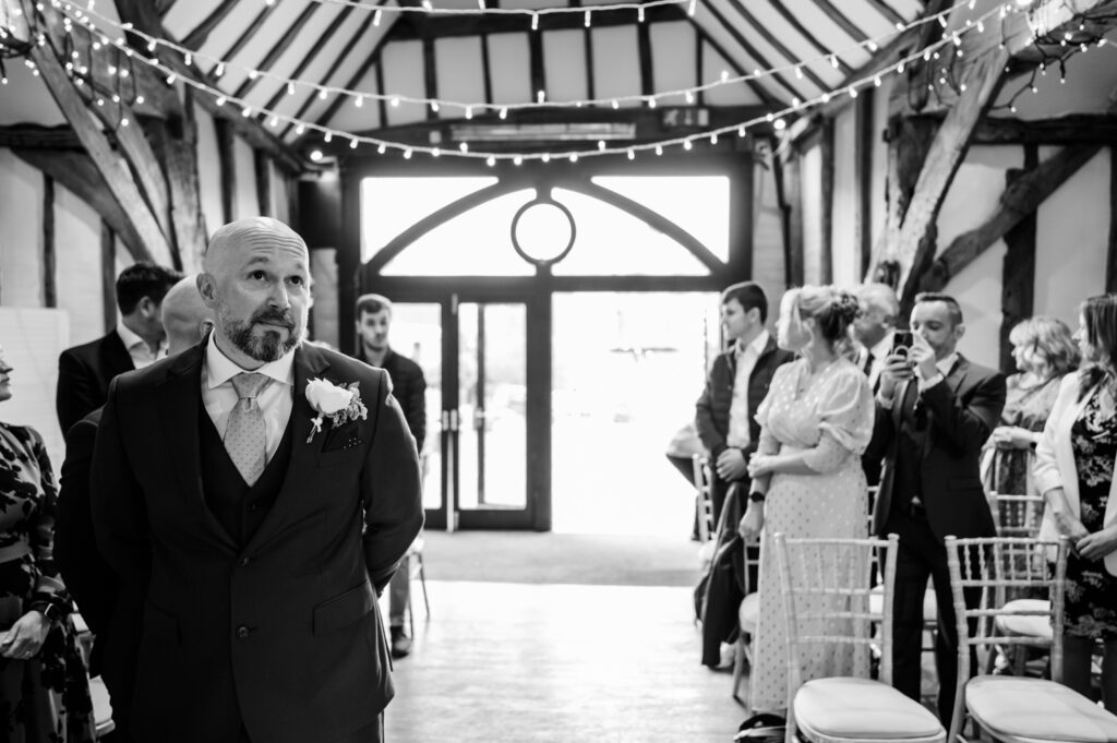 Simon standing at the aisle, waiting excitedly for Kristin during their Old Luxters Barn micro-wedding elopement.