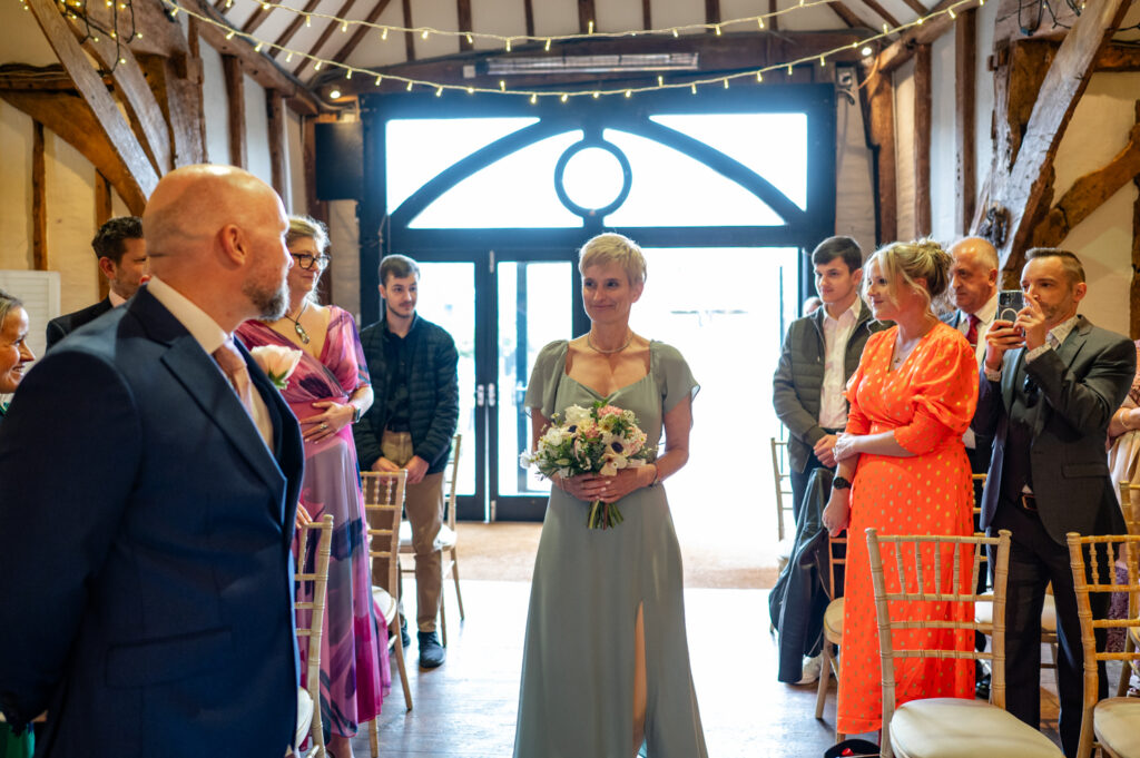 Bridesmaid walking down the aisle at Old Luxters Barn, marking the start of Kristin and Simon’s intimate micro-wedding elopement ceremony.