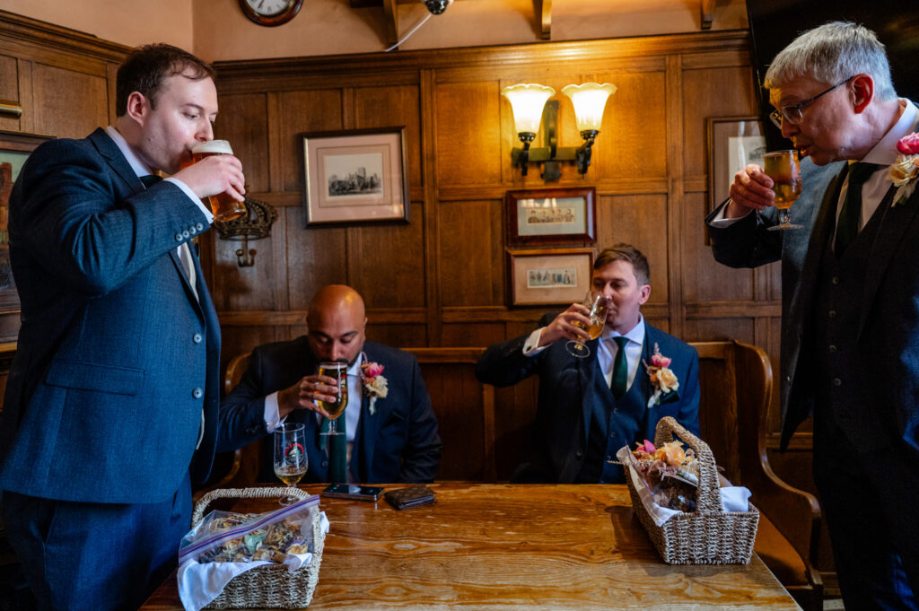 Groom raising a glass during pre-wedding preparations at a local pub.