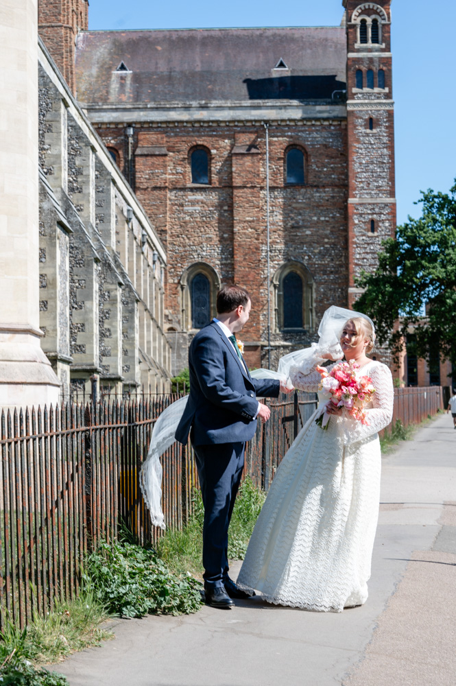 Wind catches the bride's veil at a St Albans Cathedral wedding at TewinBury Farm