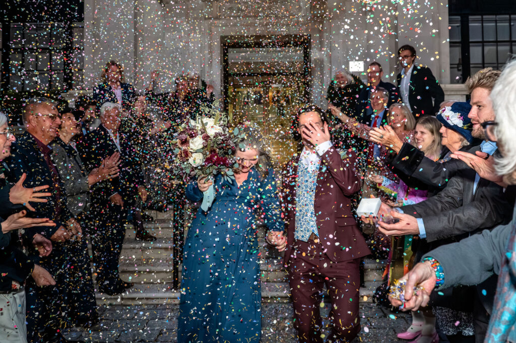 Bride and groom covered in confetti outside Islington Town Hall after their ceremony