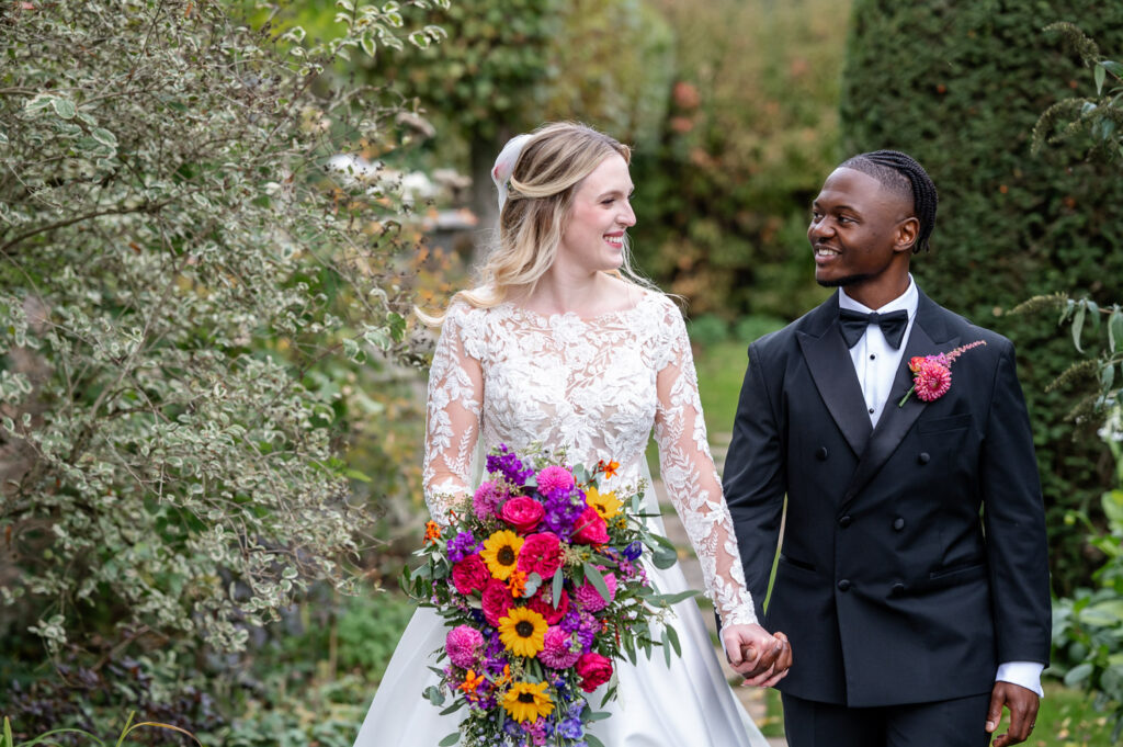 a bride and groom walk through the gardens at Chenies Manor for their couple portraits by As You Are Photography
