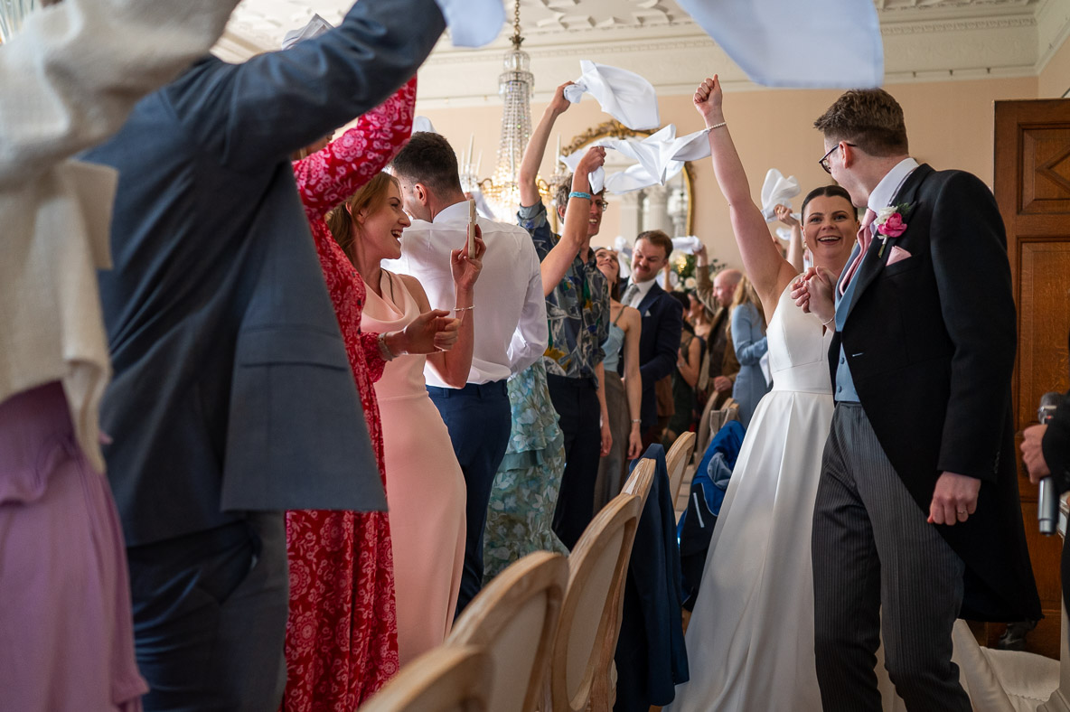 bride and groom enter the wedding breakfast with a big cheer from guests capture by hertfordshire wedding photographer